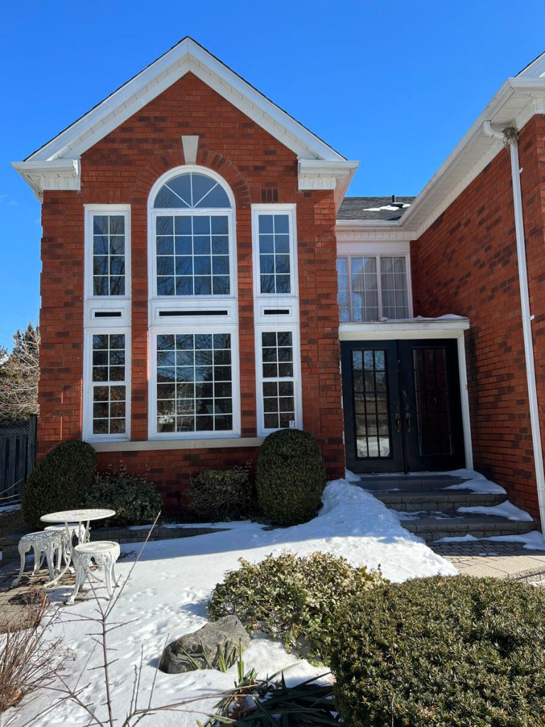 Before: Dated white vinyl windows with colonial grilles and drafty seals